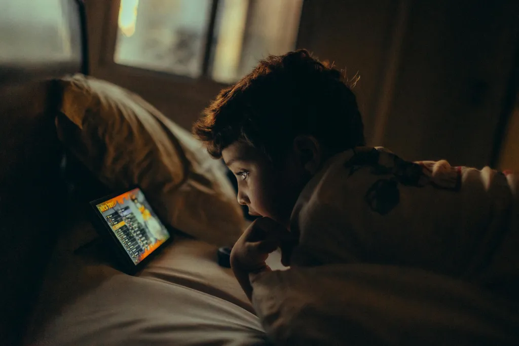 A child sitting on a sofa and watching a tablet