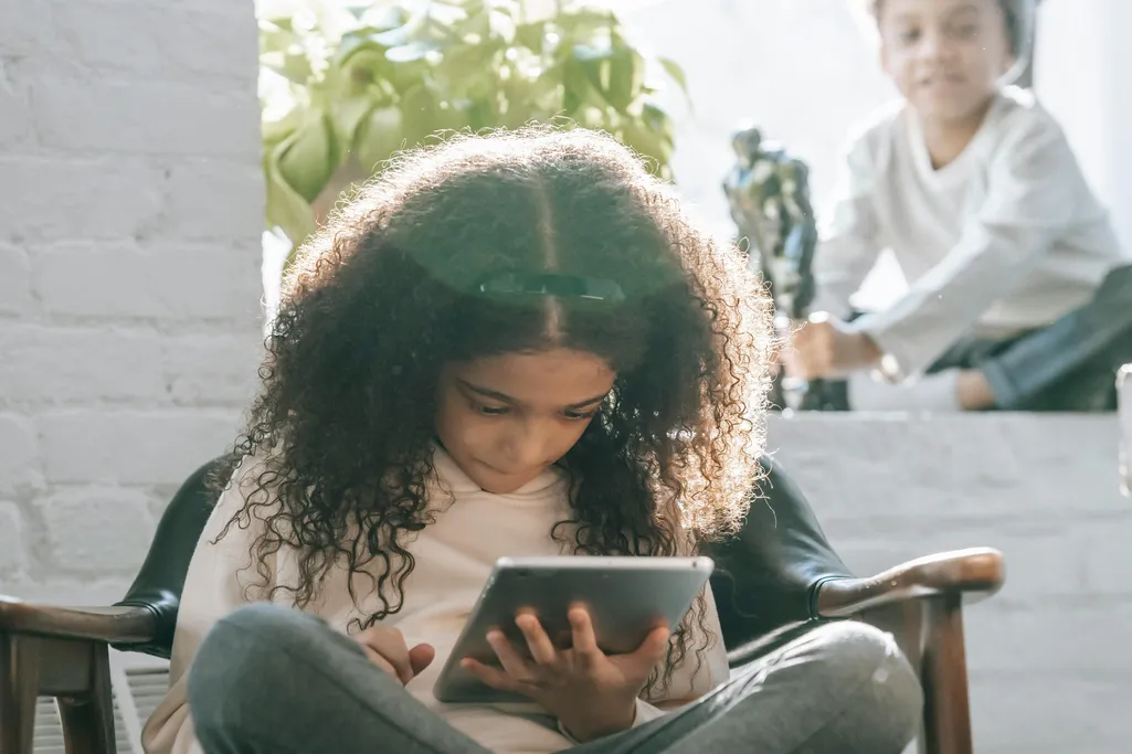 A child sitting on a sofa with a tablet