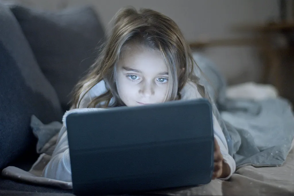 A child watching a tablet in bed