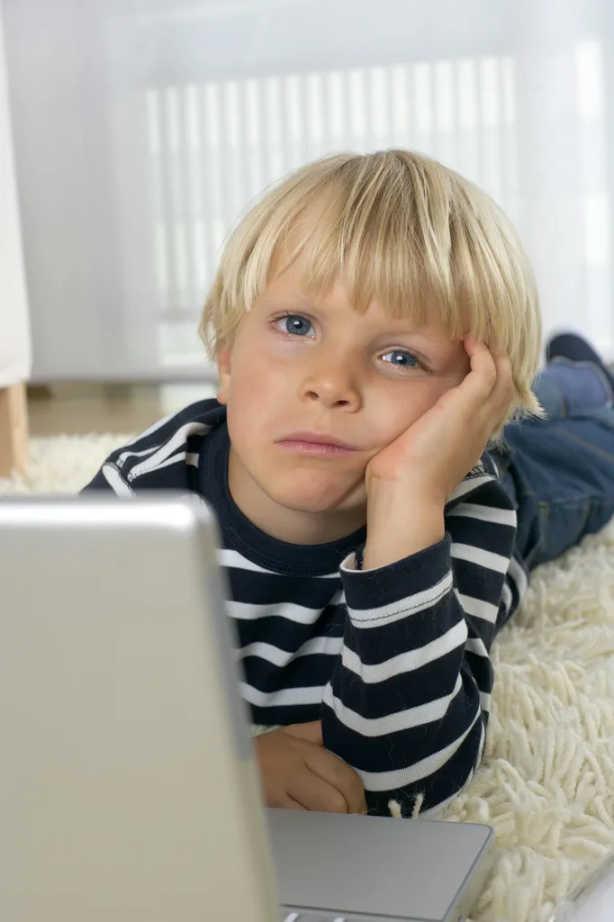 A child lying on a sofa and using a tablet